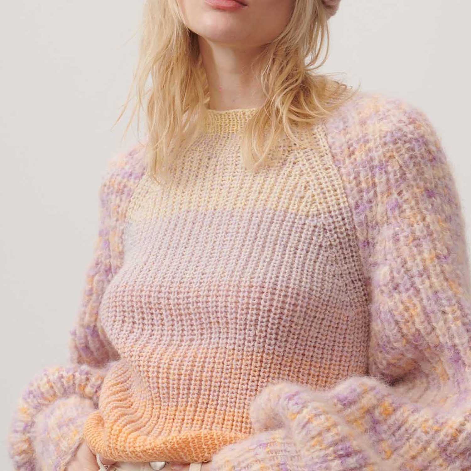 Creative Wool Dégradé Super6: Frau trägt gestrickten Pullover in Pastelltönen, weiche Textur, von Rico Design.