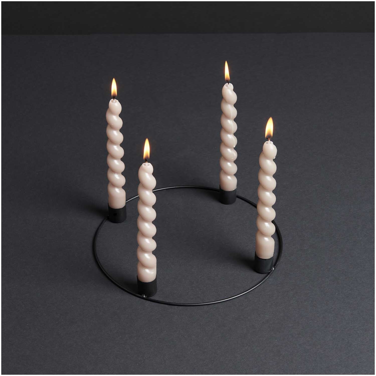 Metallring Adventskranz Ø 25cm mit vier brennenden, gedrehten Kerzen auf schwarzem Untergrund.