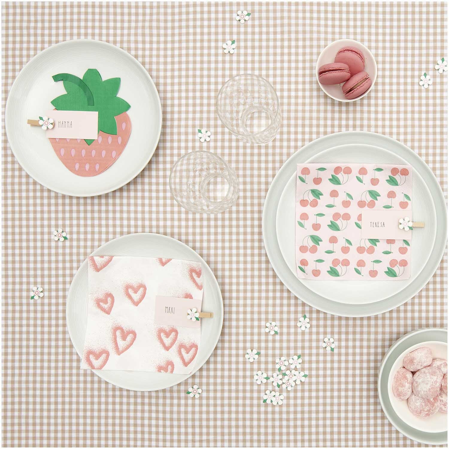 Servietten Spray Herzen 33x33cm 20 Stück von Rico Design auf einem gedeckten Tisch mit rosa Herz- und Fruchtmotiven.