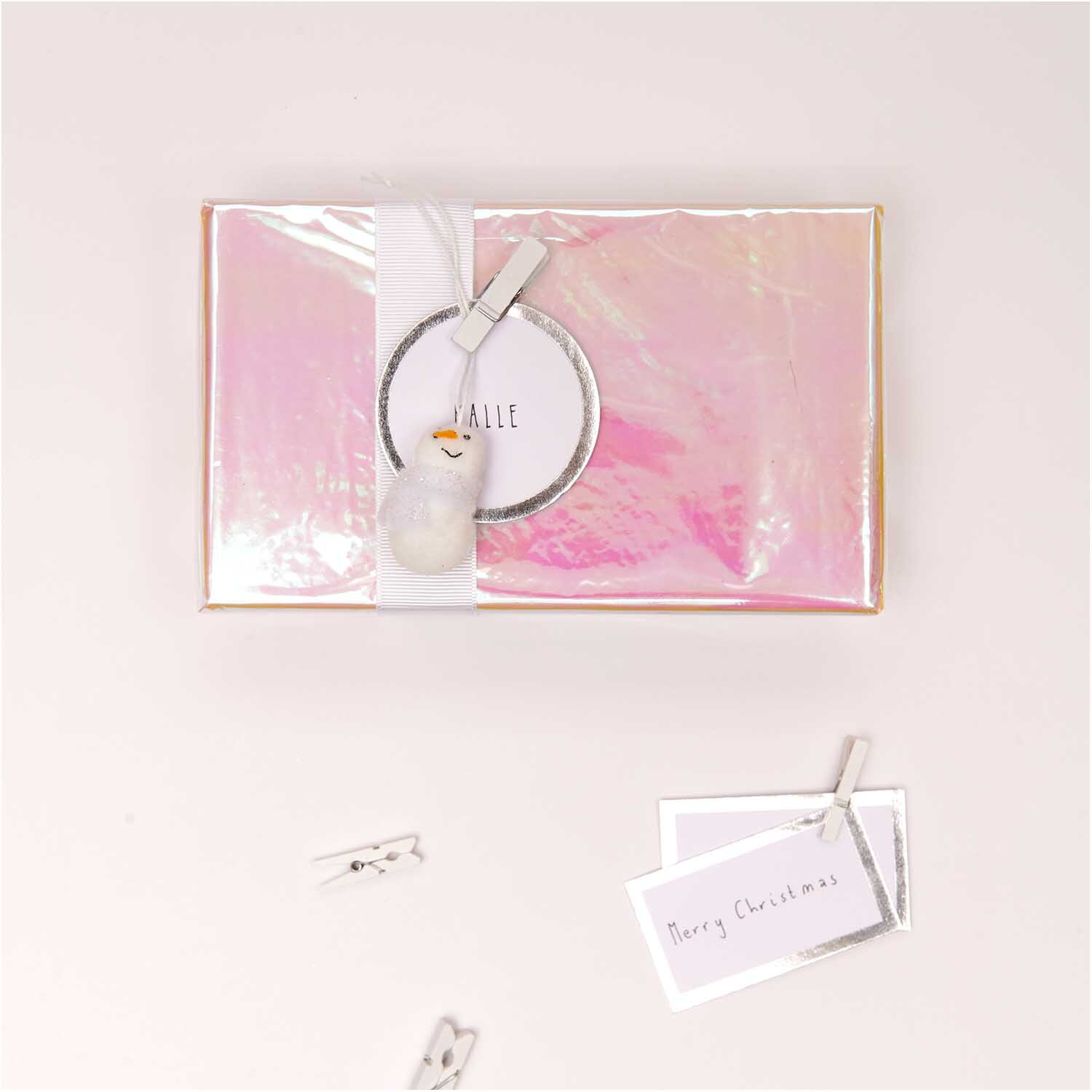 Holzklammern weiß 3,5cm 12 Stück von Rico Design auf einem rosa Geschenk mit Karte und Dekoration.