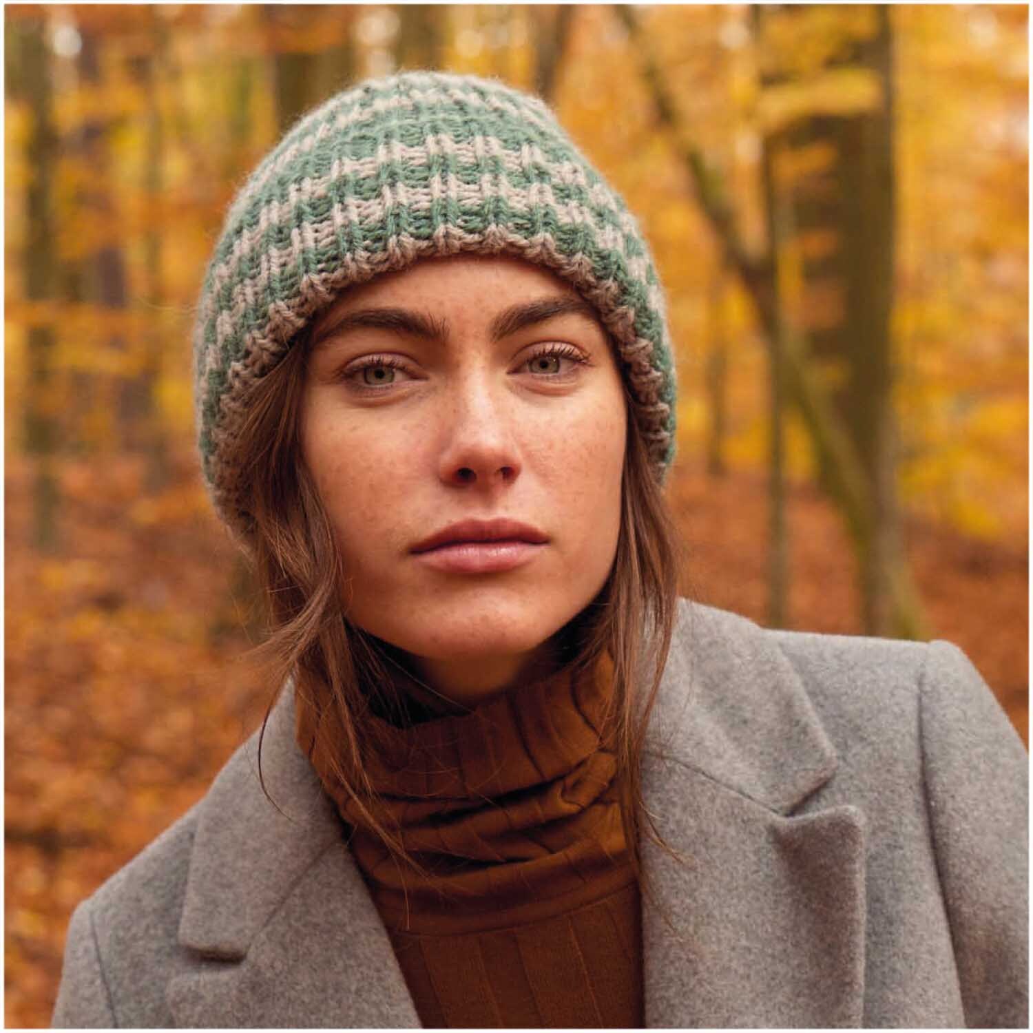 Essentials Alpaca Twist Chunky Mütze in Efeu, getragen von einer Frau im herbstlichen Wald. Ideal für kühle Tage.