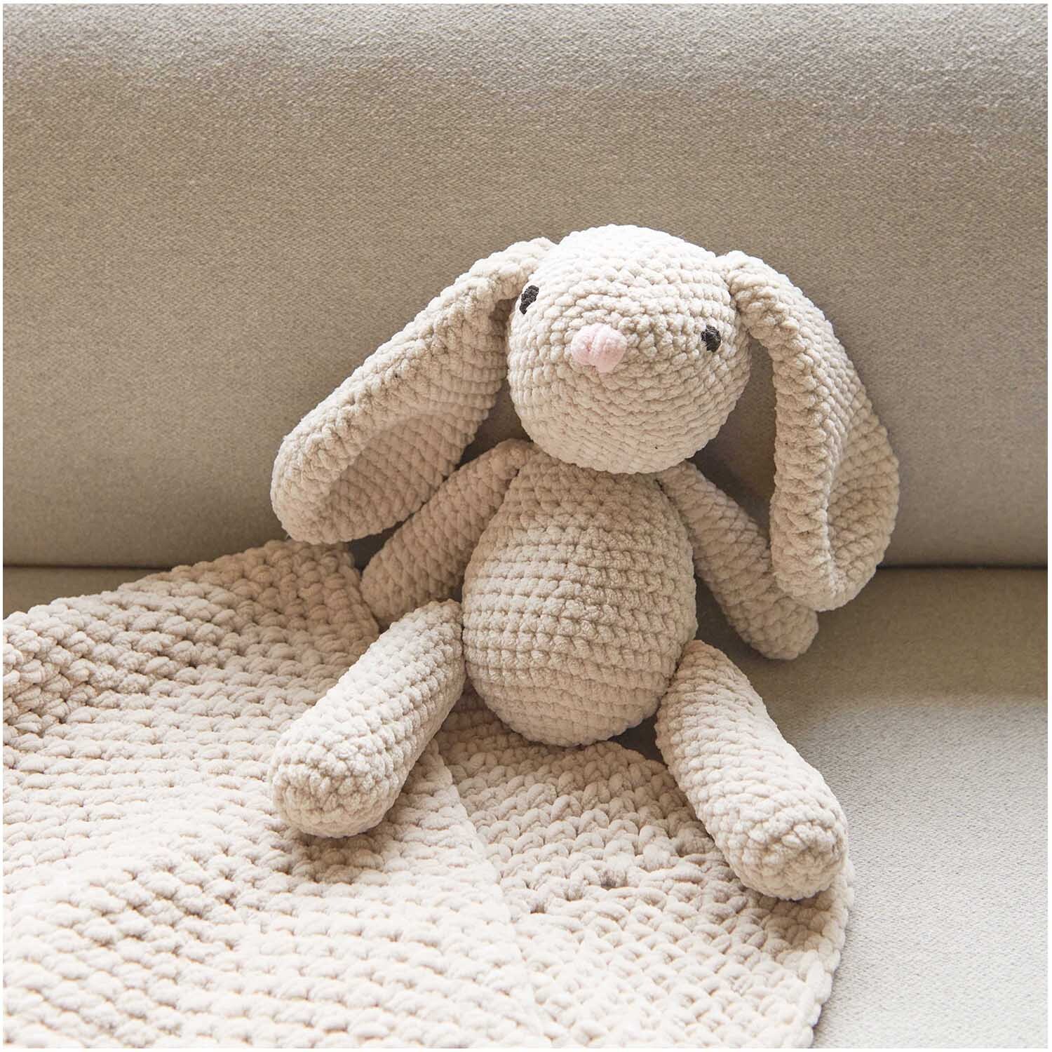 Creative Chenillove: Kuscheliger Hase aus weichem Chenille-Garn von Rico Design auf einem Sofa.