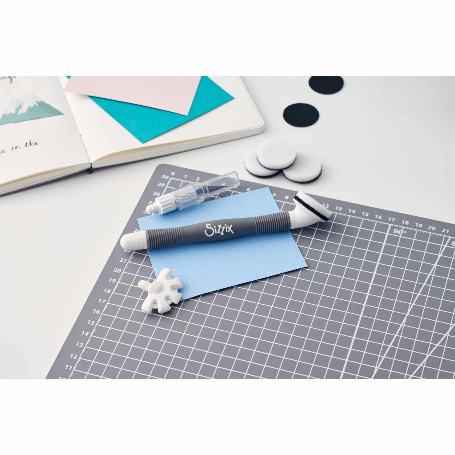 Multi-Tool Accessory Blending Tool auf einem Schneidebrett mit Bastelmaterialien und Sizzix-Logo. Ideal für kreative Projekte.