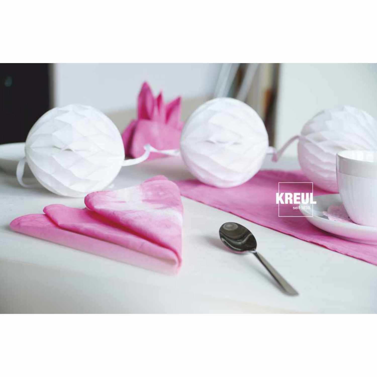Javana Batik-Textilfarbe: Rosa Tischdeko mit Servietten, KREUL-Logo, Löffel und Tasse.