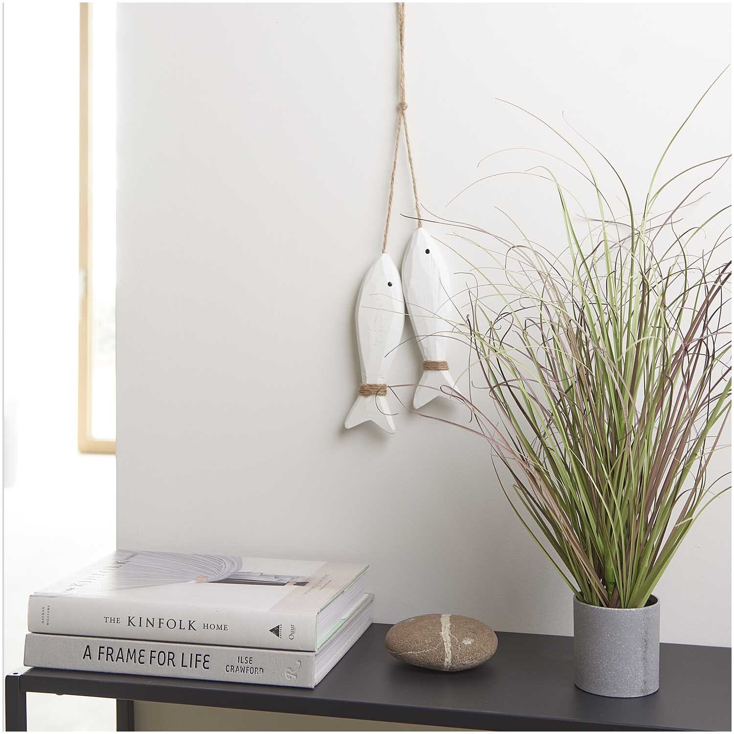 Holzhänger Fische mit Juteband weiß 19x5cm an Wand, neben Pflanze und Büchern auf Regal.