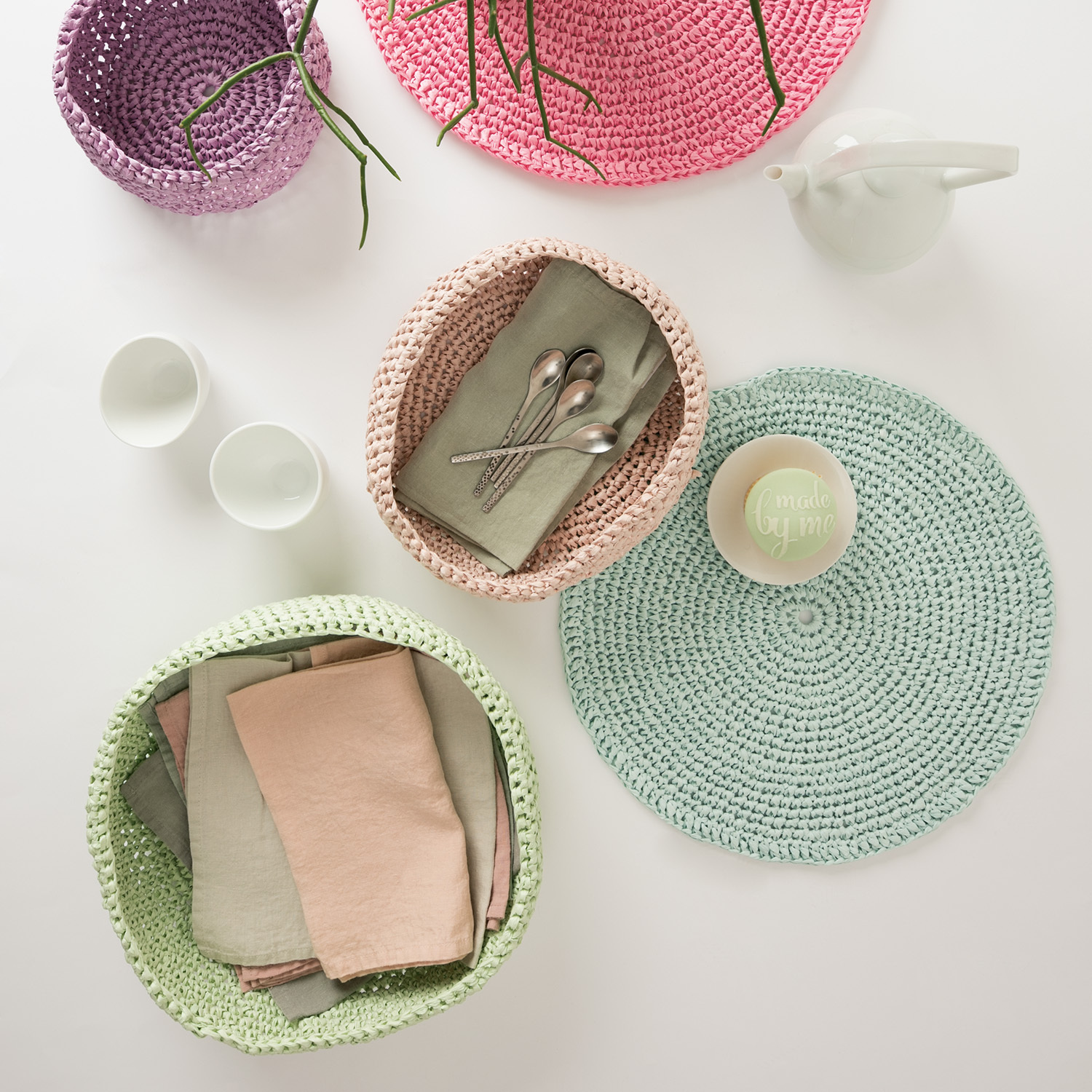Häkelanleitung Schalen aus Creative Paper: Bunte, gehäkelte Schalen mit Besteck und Servietten auf einem Tisch arrangiert.