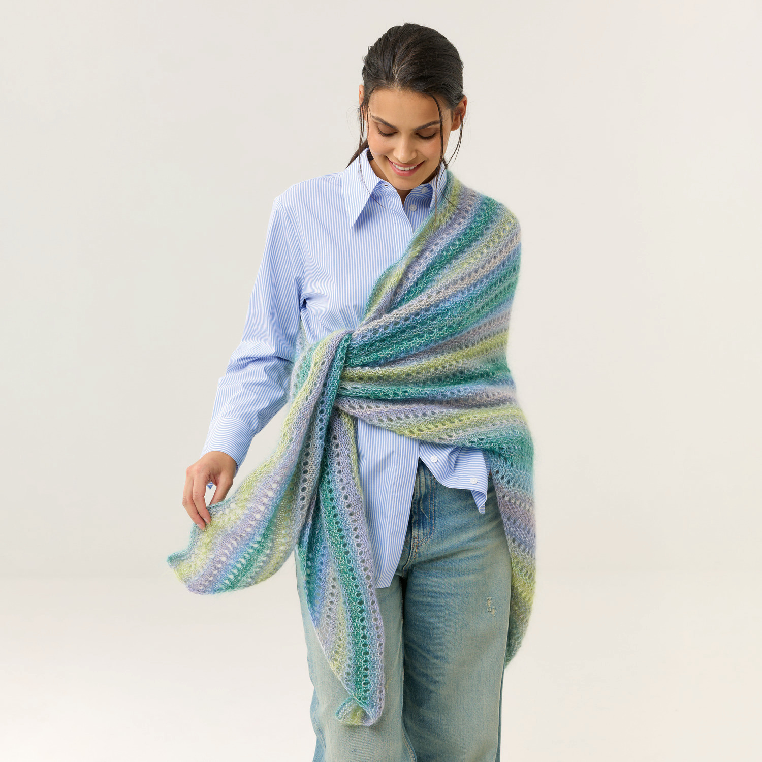 Strickset Dreieckstuch Modell 06: Frau trägt ein pastellfarbenes, doppelfädiges Tuch über Hemd und Jeans.