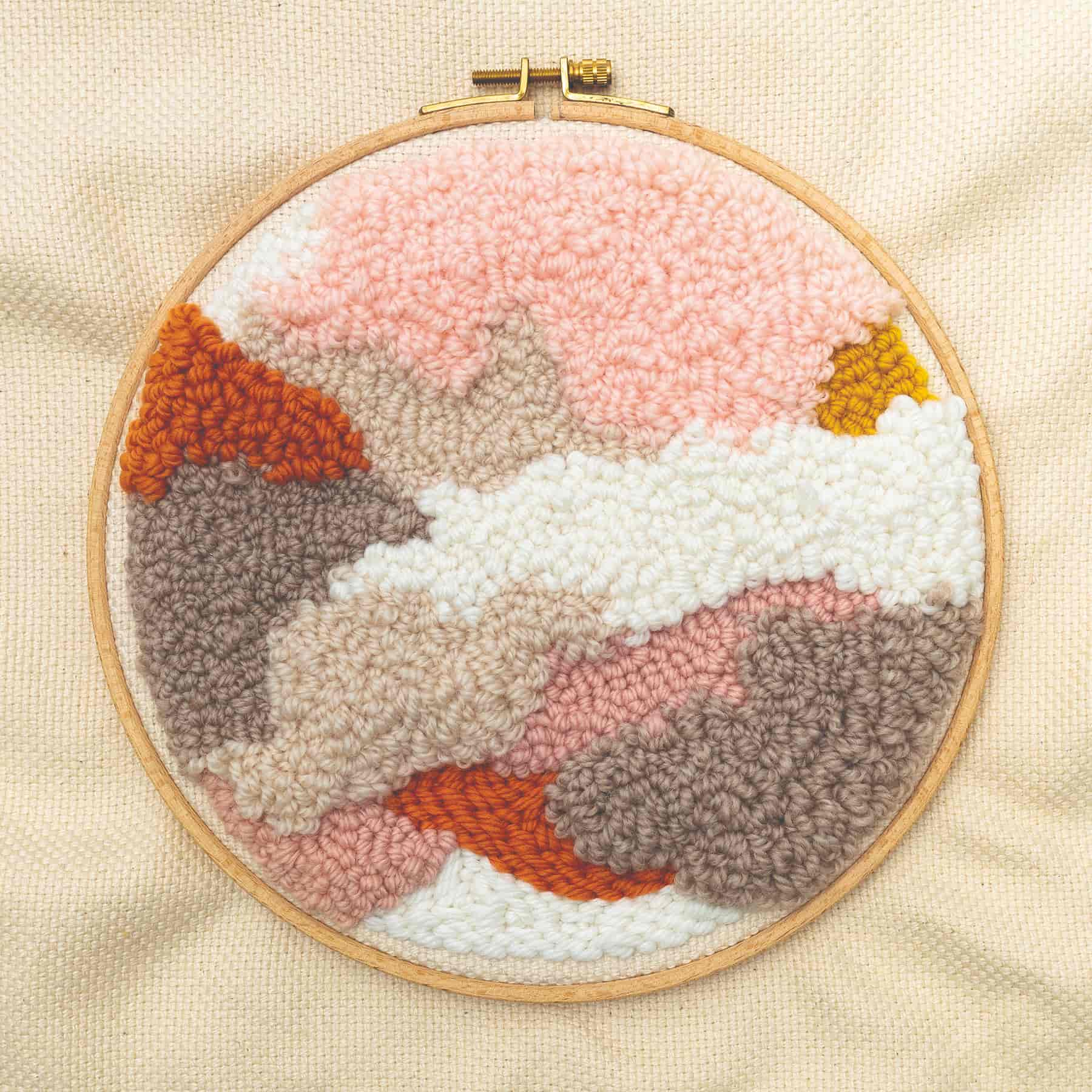 Punch Needle Motiv mit abstrakter Landschaft ist in Stickrahmen gespannt