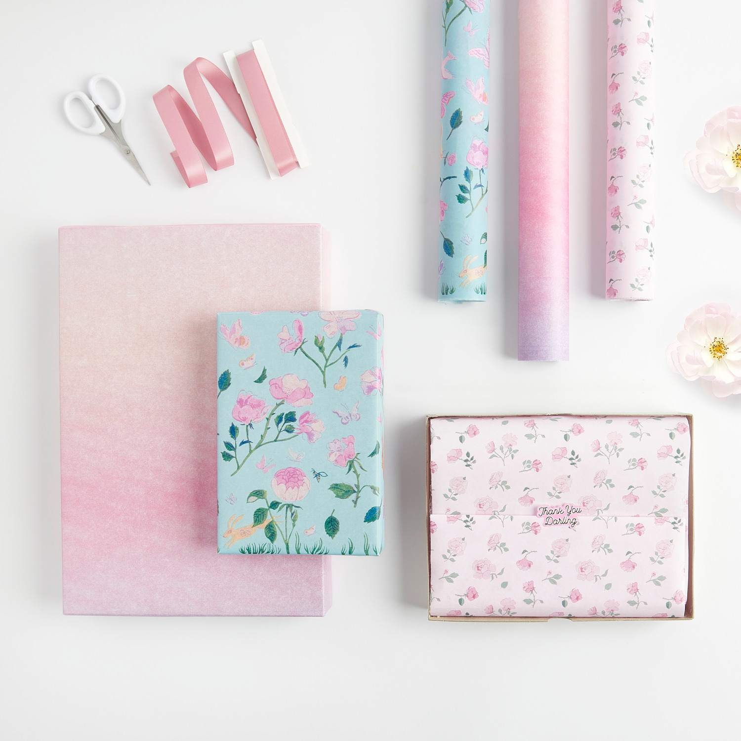 Seidenpapier Farbverlauf Rosa von Rico Design, dekoriert mit floralen Mustern und rosa Bändern, ideal für kreative Geschenkverpackungen.