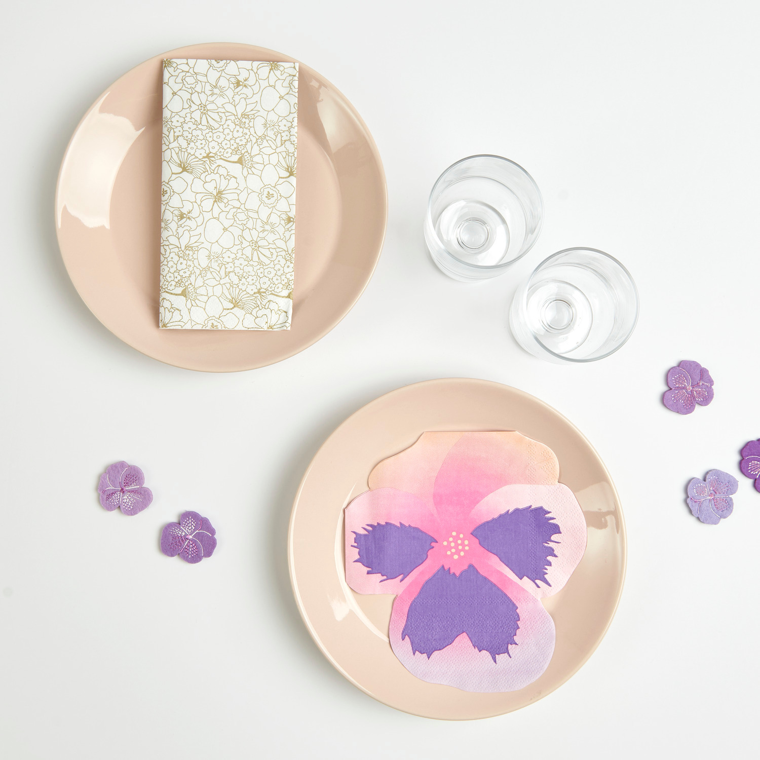 Filzstreu Stiefmütterchen bestickt Violett: Zwei Teller mit Servietten und violetten Blüten, ideal für elegante Tischdekoration.