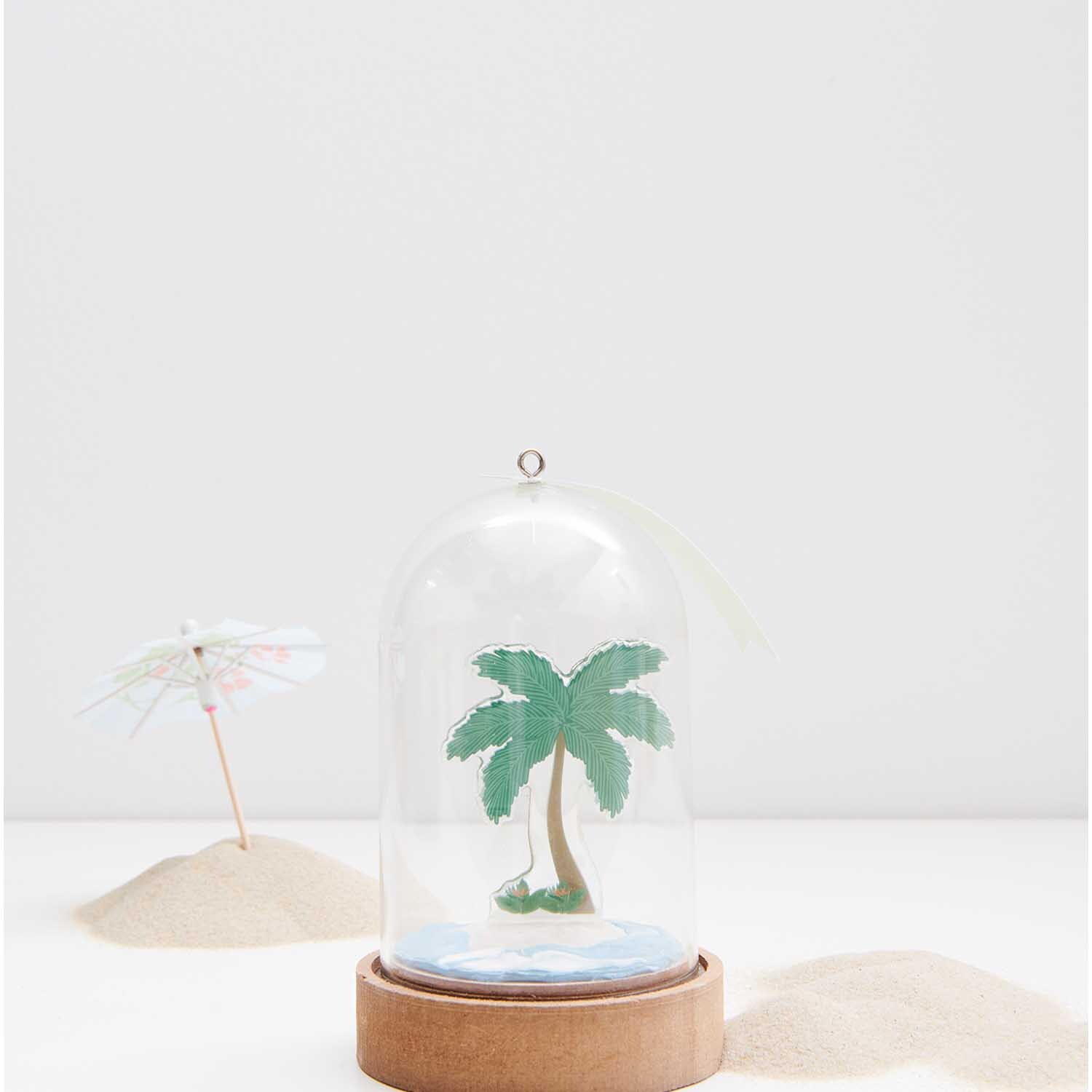 Figurico Gelsticker Tropische Pflanzen: Glaskuppel mit Palme auf Holzsockel, umgeben von Sand.