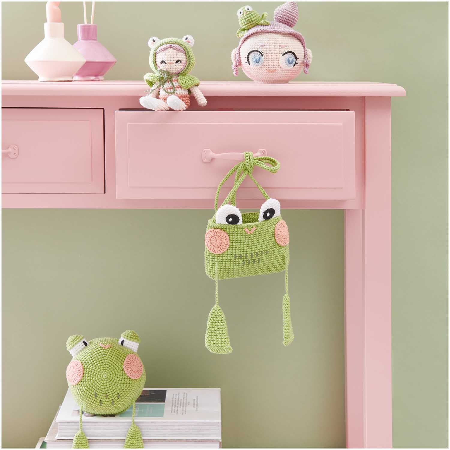 Creative Ricorumi dk: Rosa Tisch mit gehäkelten Froschfiguren und Accessoires von Rico Design.