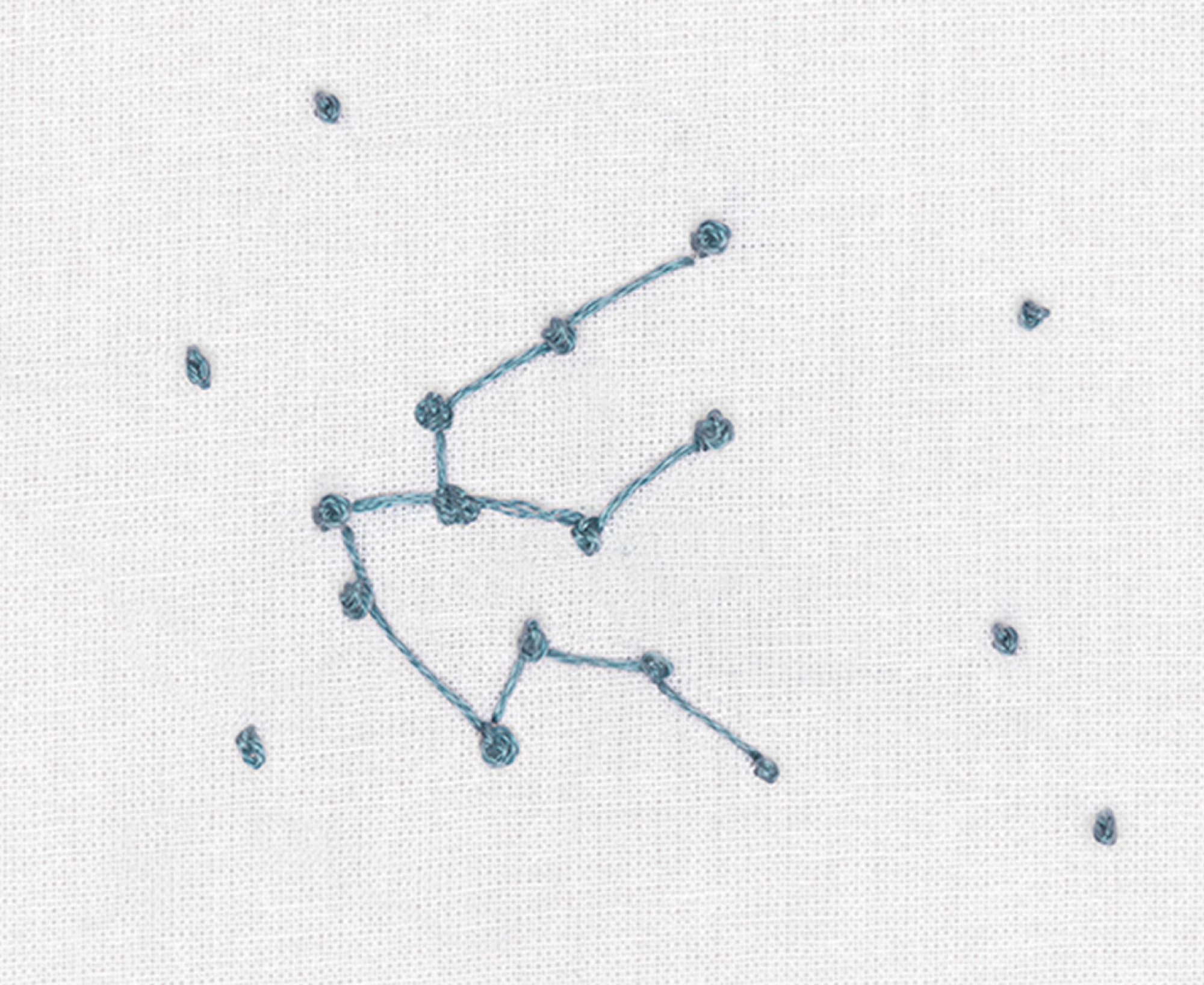 Ein abstraktes Sternenbild ist im Korallenstich auf weißen Stoff gestickt