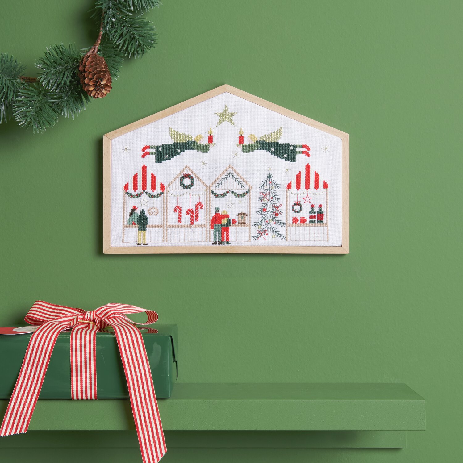Stickpackung Weihnachtsmarkt zeigt ein festliches Motiv mit Weihnachtsbuden und Tannenbaum, eingerahmt an einer grünen Wand.