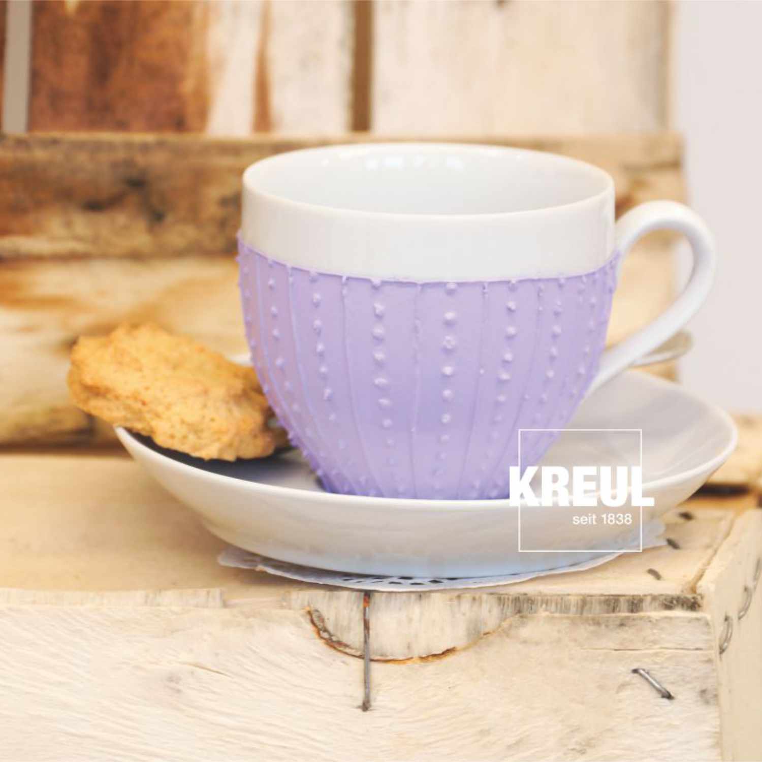 Glas- und Porzellanfarben Set Chalky: Weiße Tasse mit lila Muster, Keks auf Untertasse, Marke KREUL.
