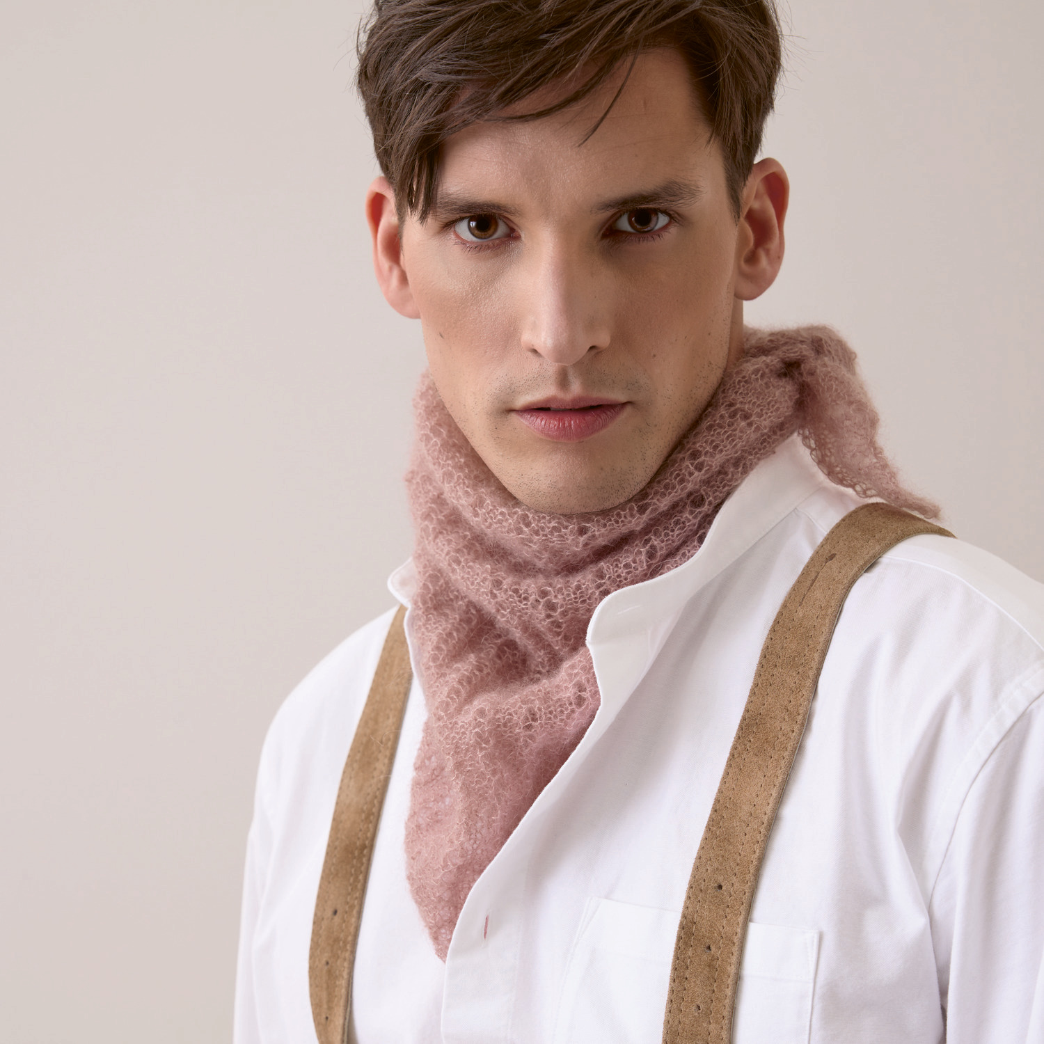 Strickset Dreieckstuch Modell 08: Mann trägt rosa Tuch aus Trachtenbuch I mog di, kombiniert mit weißem Hemd und Hosenträgern.
