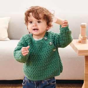 Kleines Kind trägt grünen Strickpullover.