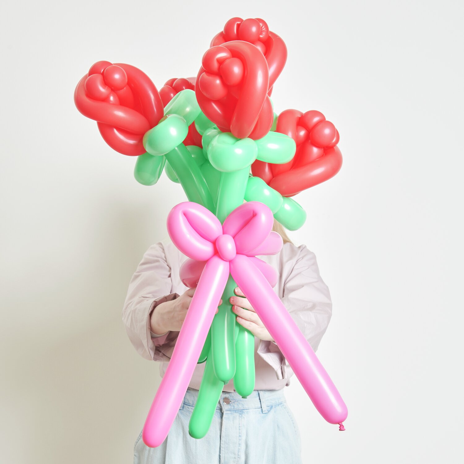 Ballonstrauß Rosen Rot von Rico Design: Ein Strauß aus roten und grünen Ballons, kunstvoll gebunden, gehalten von einer Person.