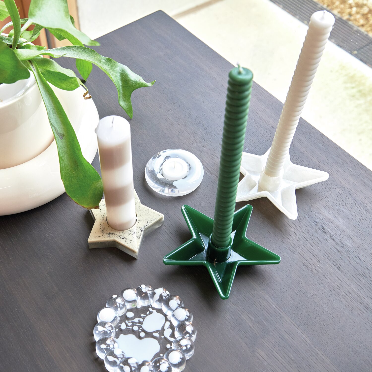 UV Resin: Verschiedene Kerzenhalter in Sternform auf einem Tisch, umgeben von Pflanzen und Dekoration. Ideal für kreative Designs.