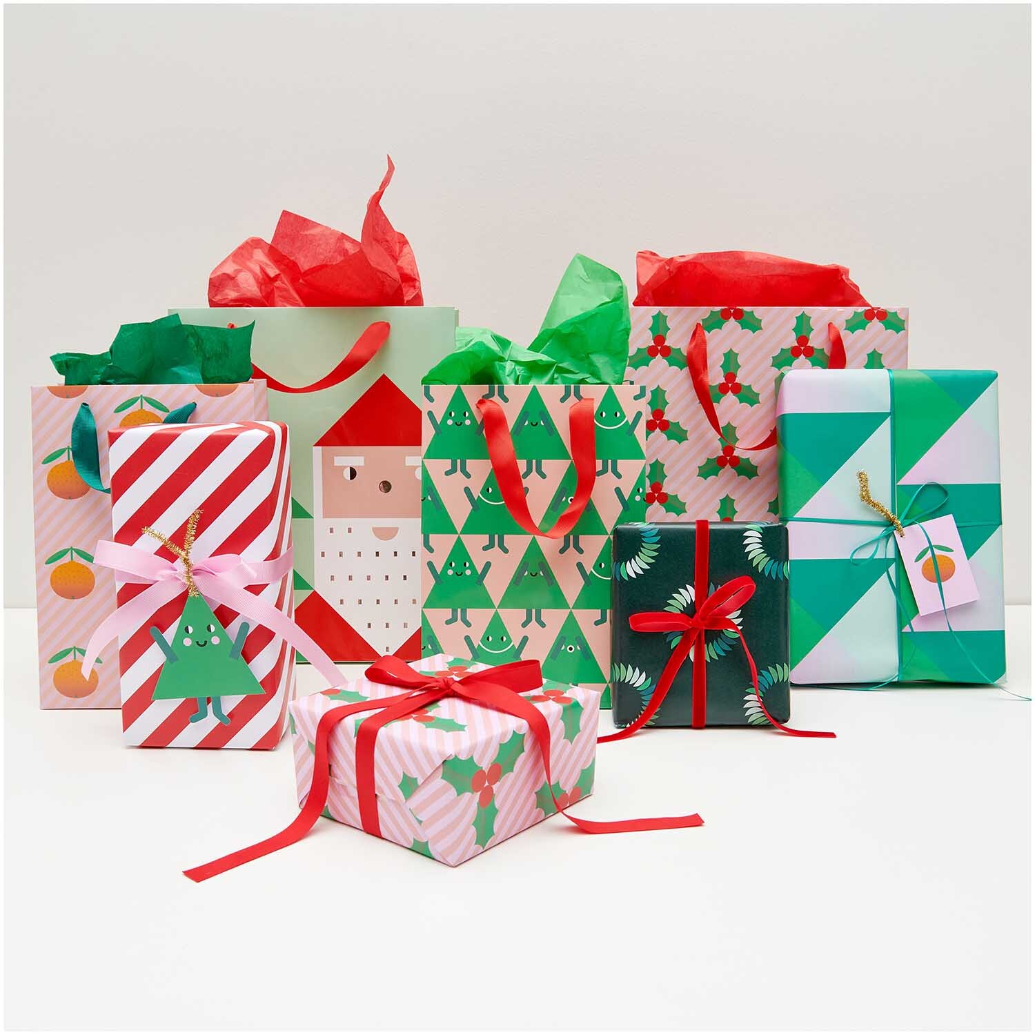Paper Poetry Geschenktüte Weihnachtsmann zeigt bunte Geschenke mit festlichen Mustern und Schleifen. Perfekt für weihnachtliche Anlässe.