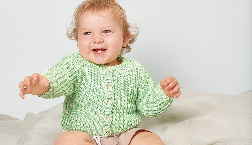 Strickanleitung Jacke aus Rico Baby Cotton Soft dk: Lächelndes Baby in mintgrüner Strickjacke.