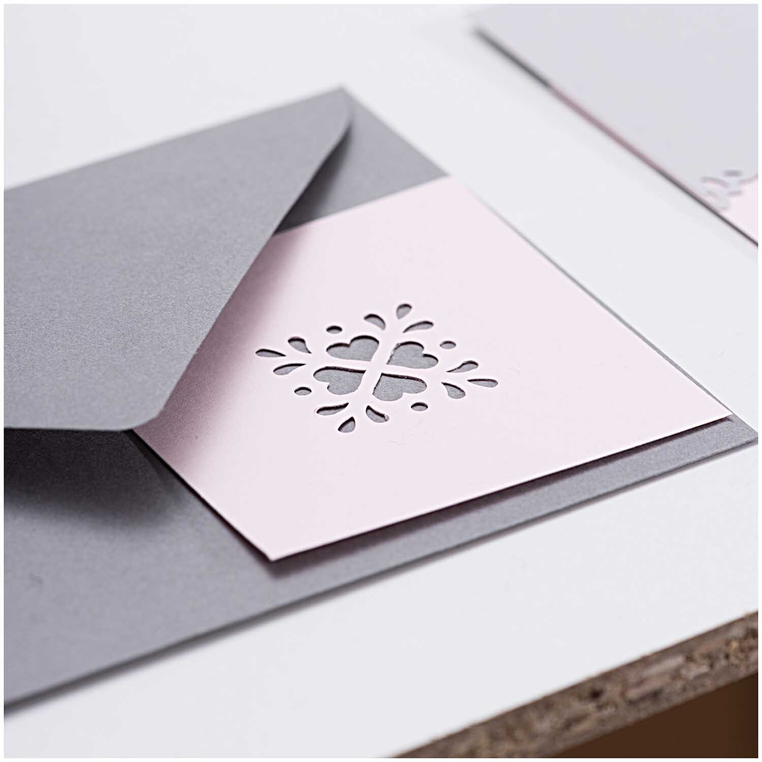 Paper Poetry Everywhere Stanzer Ornament 3x3cm von Rico Design, zeigt ein filigranes Muster auf rosa Papier in einem grauen Umschlag.
