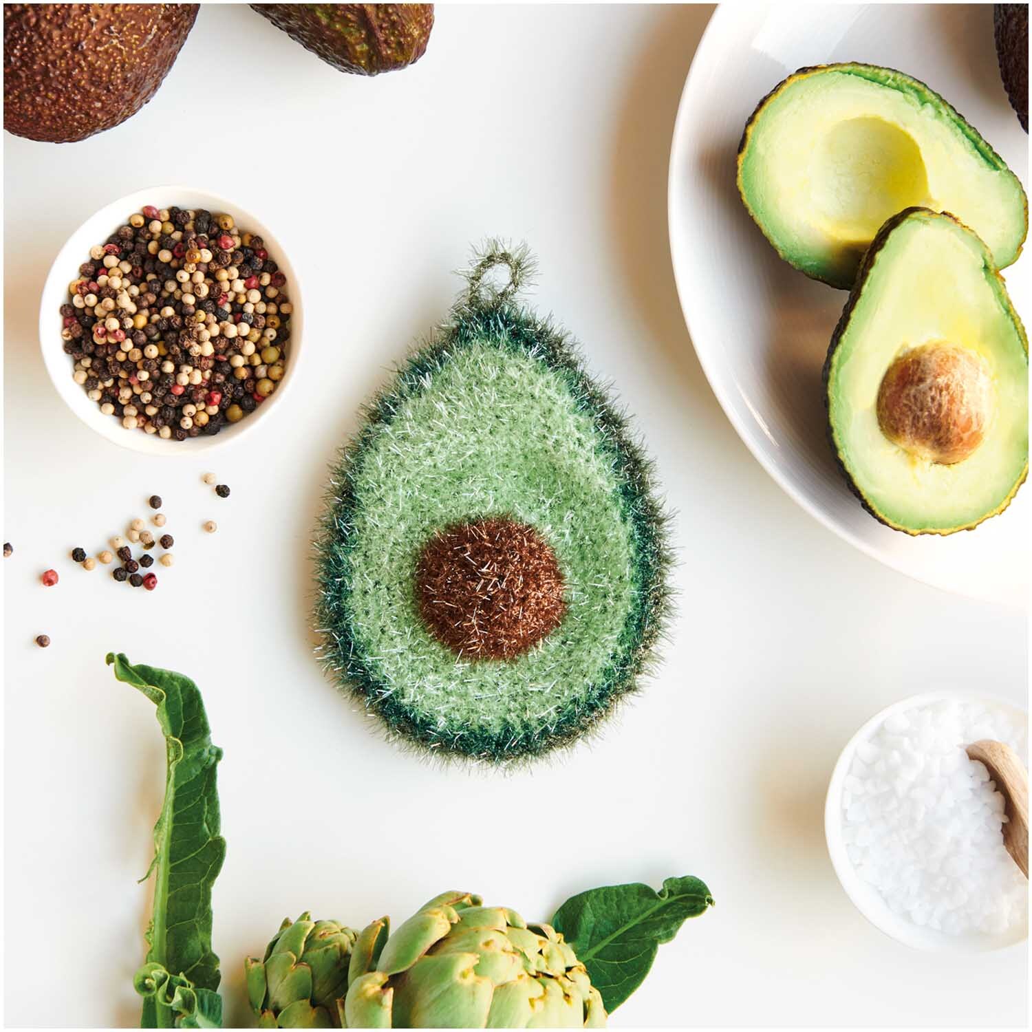 Creative Bubble: Schwamm in Avocado-Form, umgeben von Gewürzen und Gemüse. Perfekt für kreative Küchenideen.