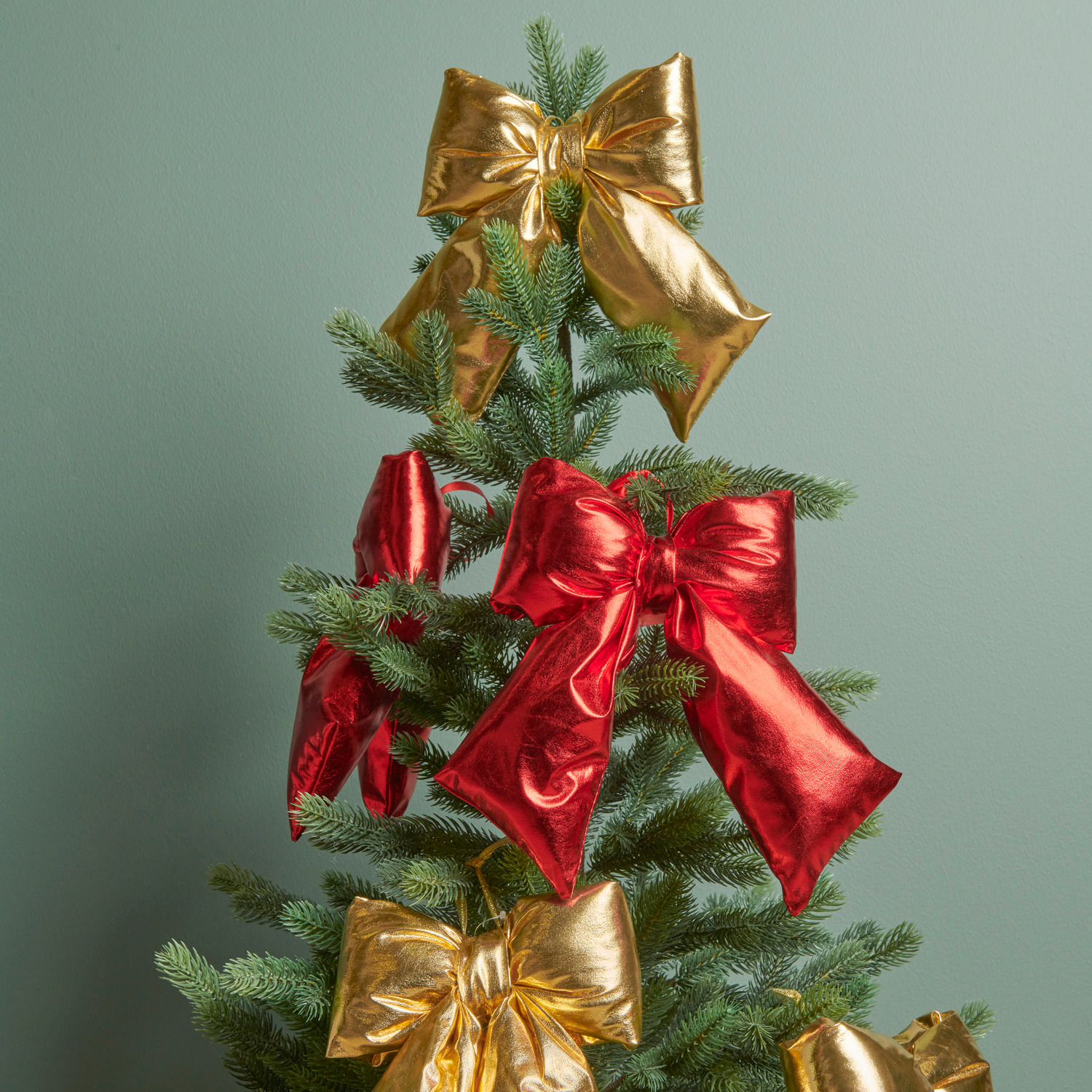 Weihnachtsschleife Gold: Festliche Schleifen in Gold und Rot schmücken einen grünen Tannenbaum.