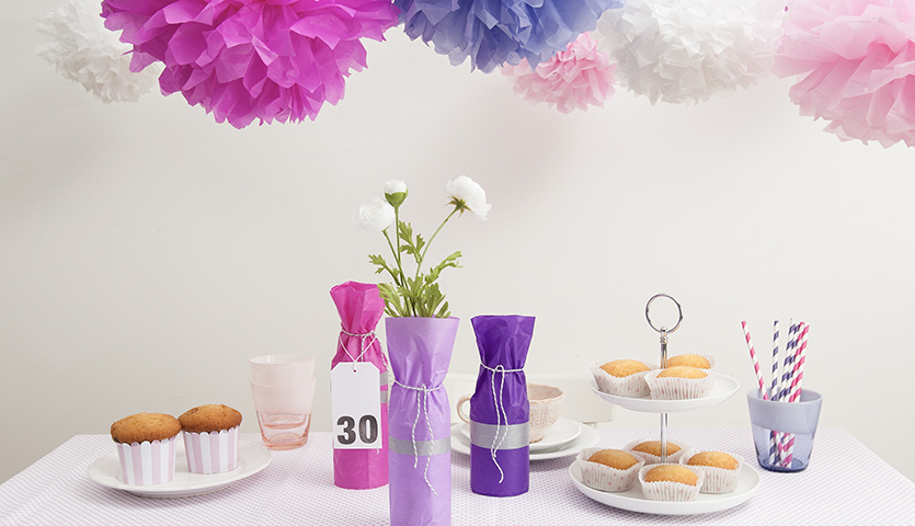 Bastelanleitung Partydeko selber machen: Tisch mit Cupcakes, Blumen und bunter Papierdeko.