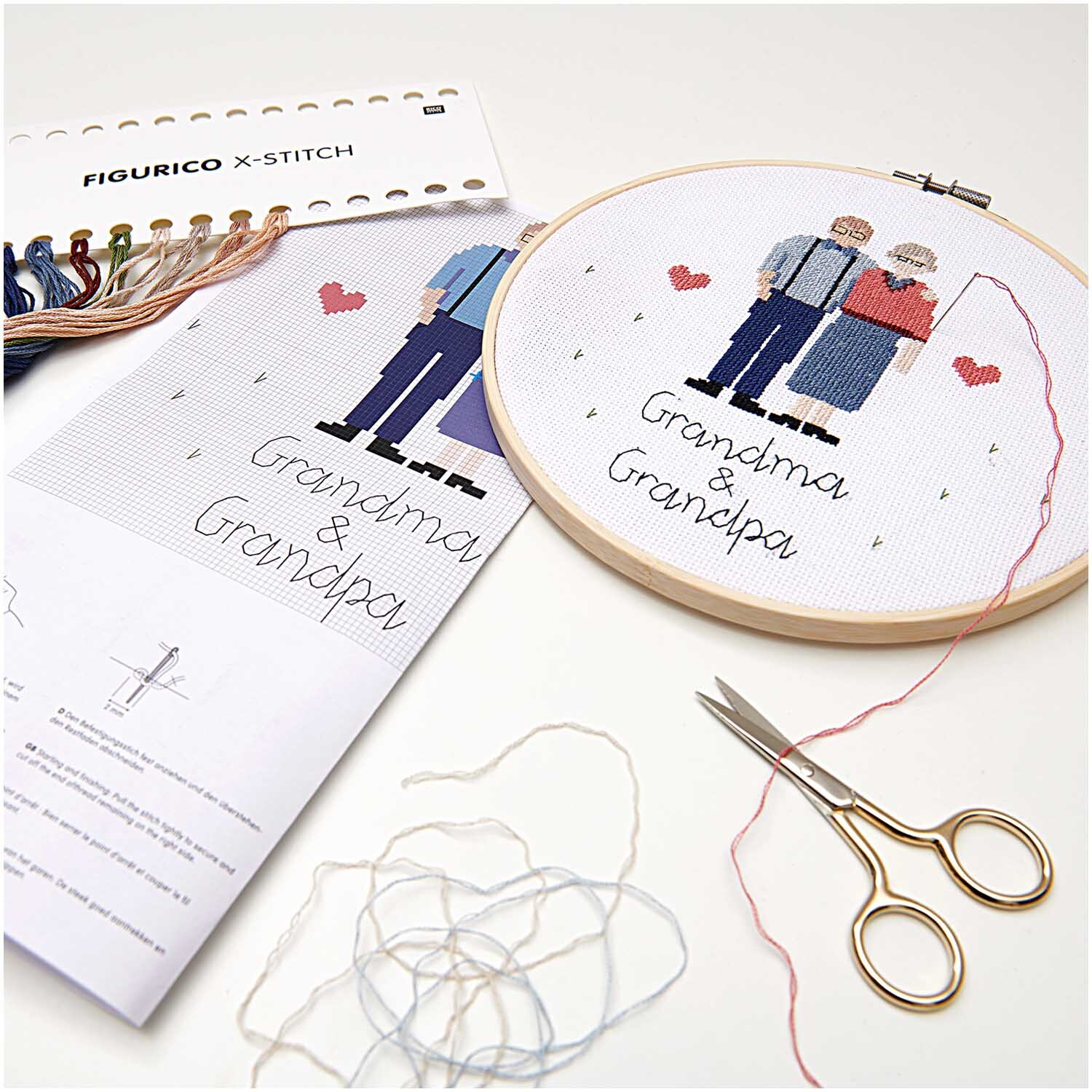 Figurico Stickpackung Grandma & Grandpa 20cm zeigt ein Stickset mit Garn, Schere und Anleitung.