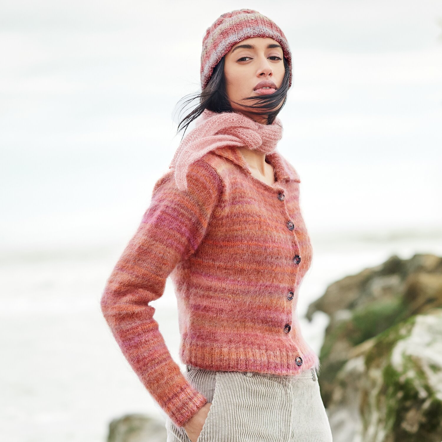 Strickset Minituch Modell 41: Frau in rosa Strickjacke und Mütze am Strand, Lovewool No. 21.