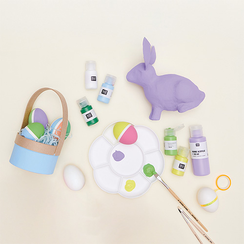 Bemalter Osterhase und Ostereier im Korb dazu Farbe in verschiedenen Farben mit Pinsel. Flatlay von Produkten.