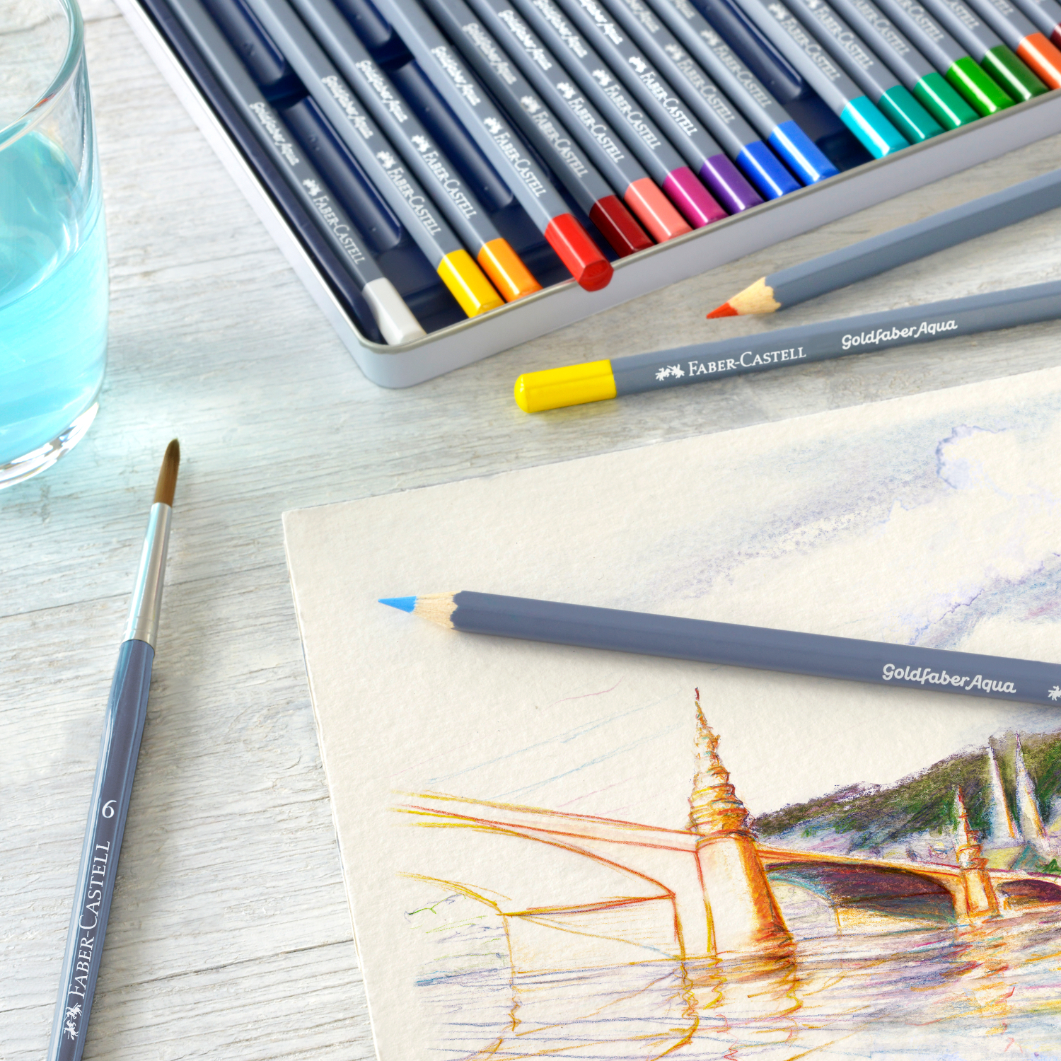 Goldfaber Aqua Aquarellstifte Pastell im Metalletui, 12-teilig, mit Pinsel und Zeichnung auf Holzoberfläche.