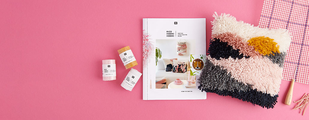 Kissen mit Knüpftechnik, Anleitungsheft und Zubehör. Flatlay von Produkten.