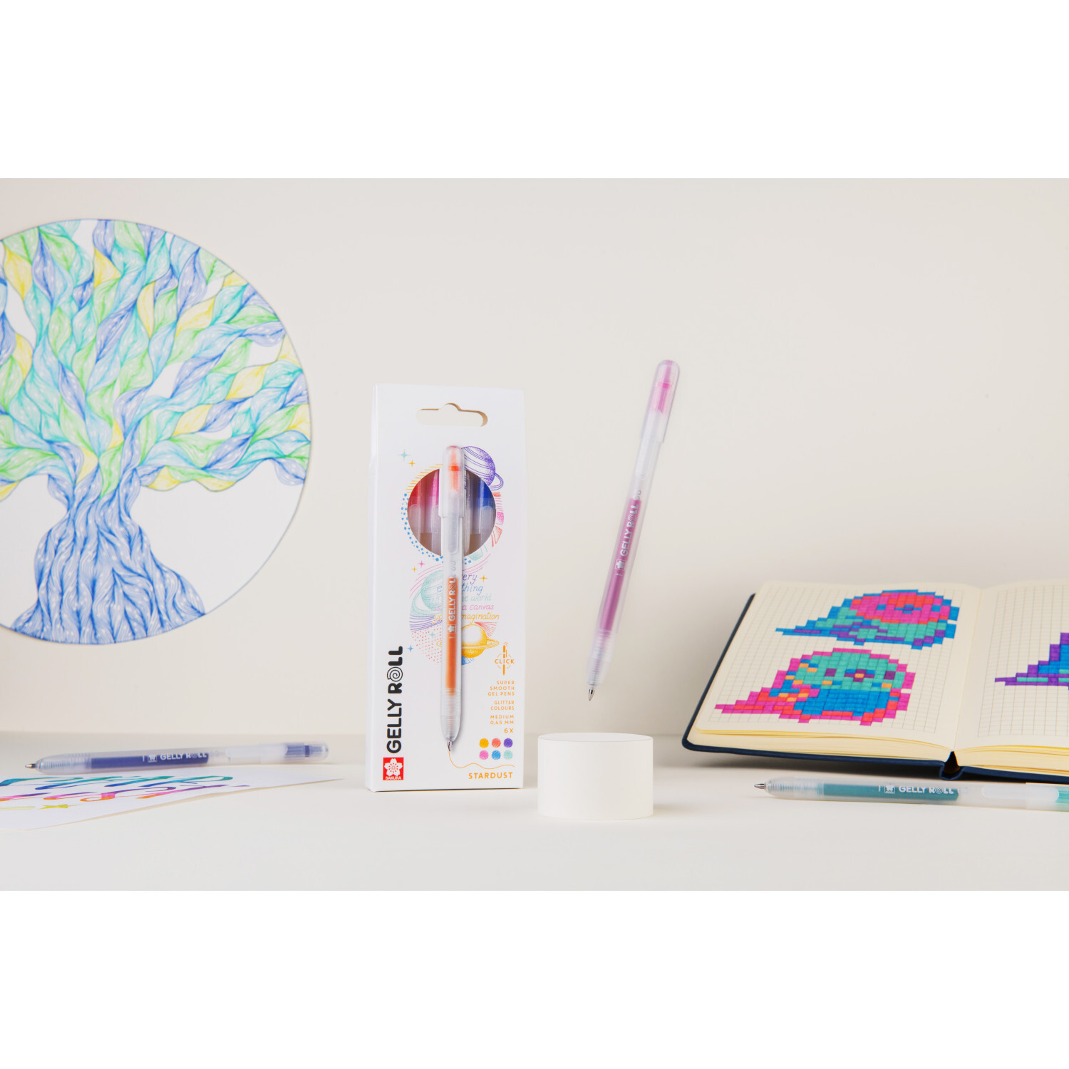Gelly Roll Retractable Set Stardust mit 6 Stiften von SAKURA, umgeben von bunten Zeichnungen und einem Notizbuch.