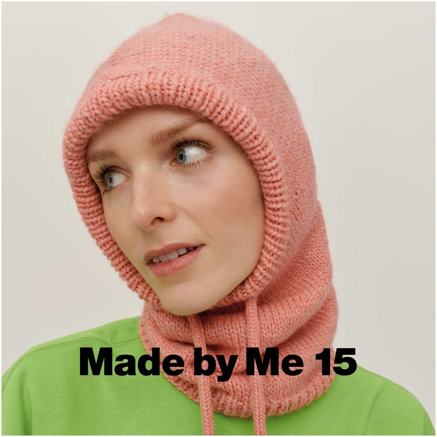 Essentials Super aran: Frau trägt lachsfarbenen Strick-Balaclava von Rico Design, passend zu grünem Oberteil.