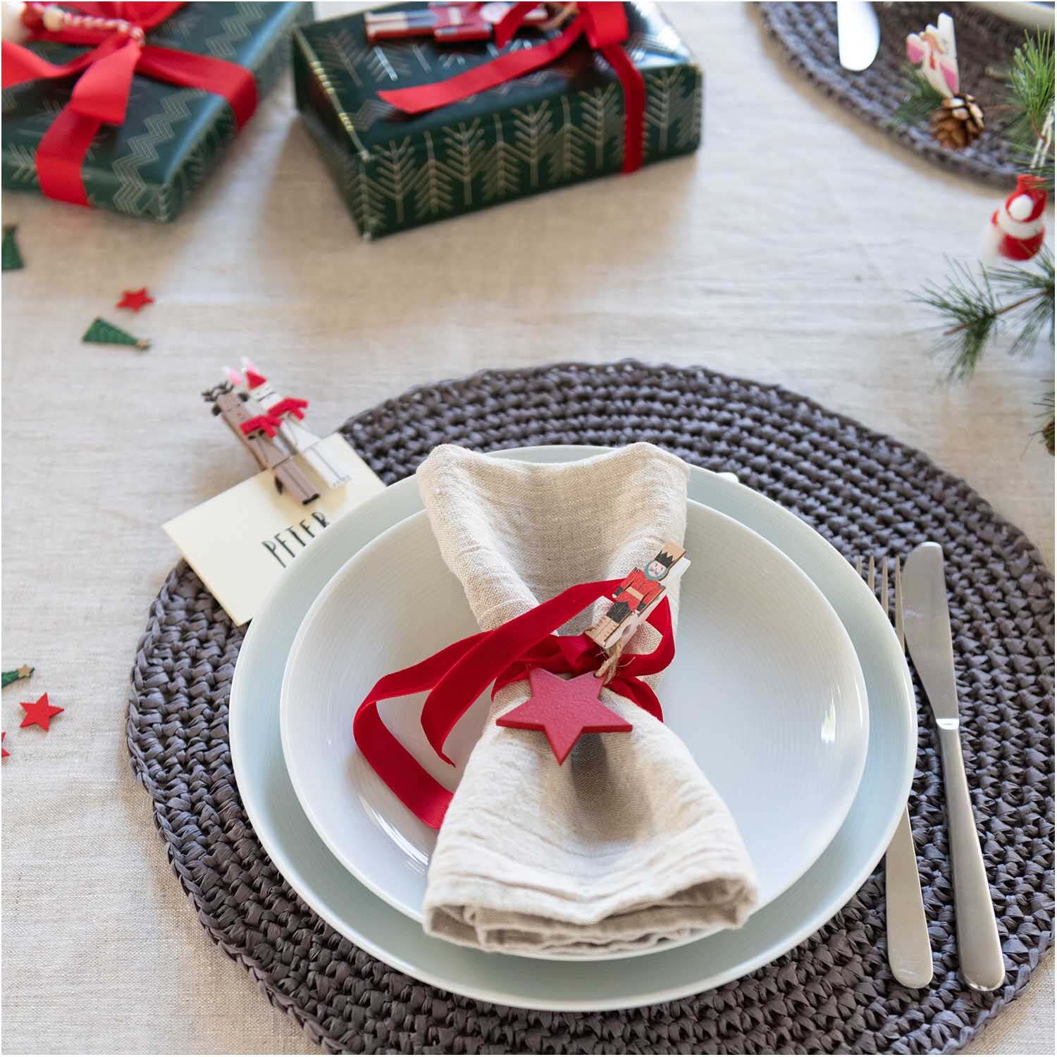 Holzstreu Tannenbaum 15x30mm 48 Stück: Festliche Tischdekoration mit Geschenk, Besteck und Serviette auf grauem Platzdeckchen.