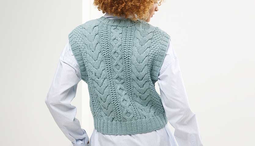 Strickanleitung Pullunder aus Classik: Rückansicht eines blauen, gestrickten Pullunders über einem weißen Hemd.