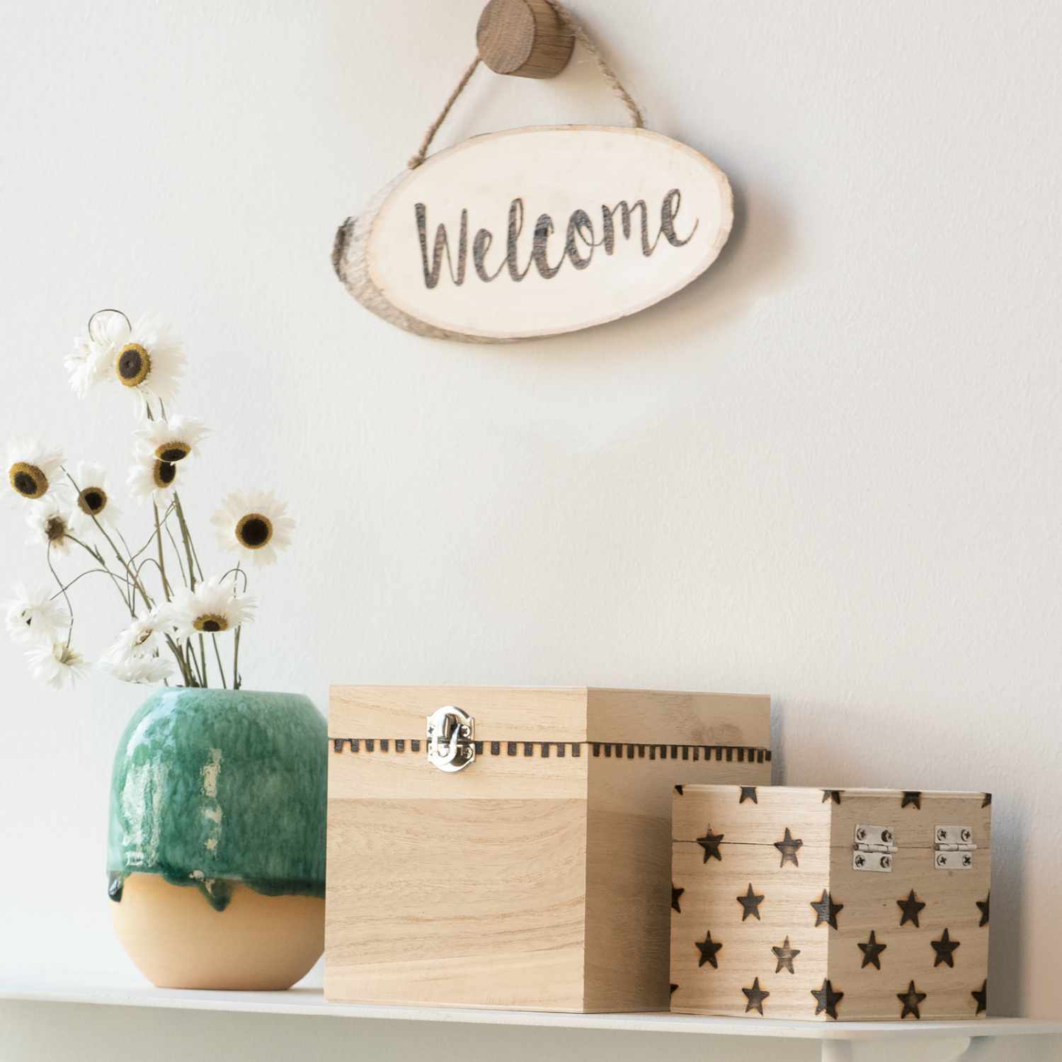 Anleitung Holzdeko mit Brandmalerei verzieren: Holzboxen mit Sternen und Blumen neben einem grünen Keramiktopf und einem "Welcome"-Schild.