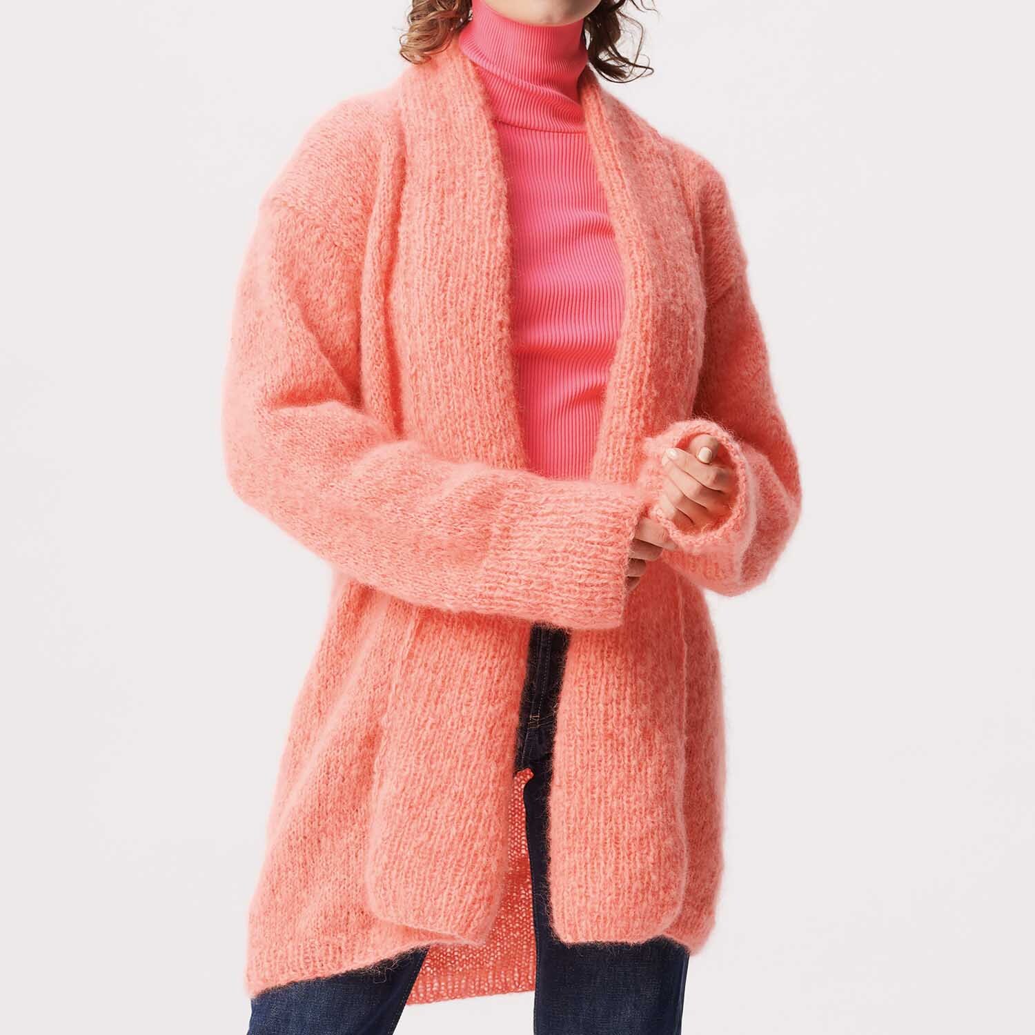 Strickanleitung Jacke aus weichem Mohair-Merino-Garn in leuchtendem Koralle, getragen von Frau.