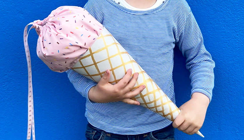 Nähanleitung Eis-Schultüten: Kind hält eine Schultüte in Eiswaffel-Optik mit rosa Stoff.