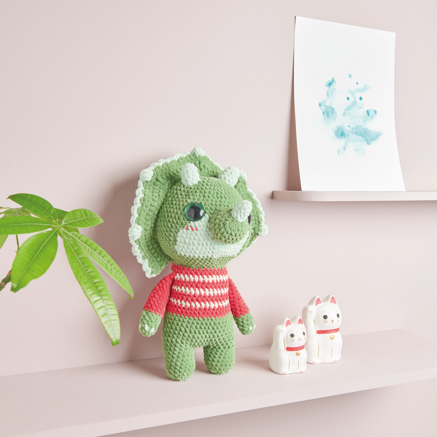 Häkelset Baby Dinosaur Modell 01: Grüner Dinosaurier aus Chenillove Big Cuties auf Regal mit Deko.