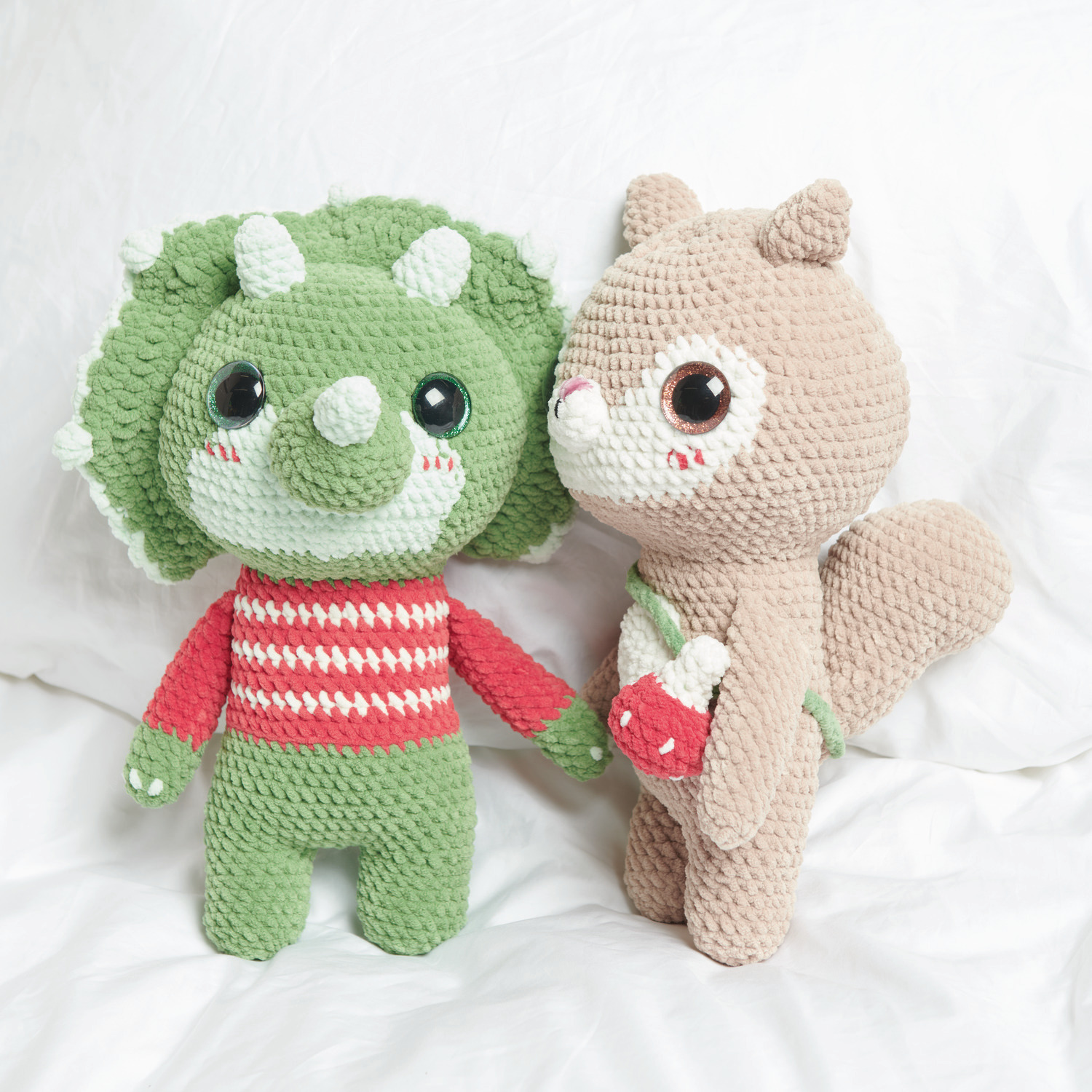 Häkelset Little Squirrel Modell 02: Ein beige Eichhörnchen und ein grüner Dinosaurier aus Chenillove Big Cuties auf weißem Hintergrund.