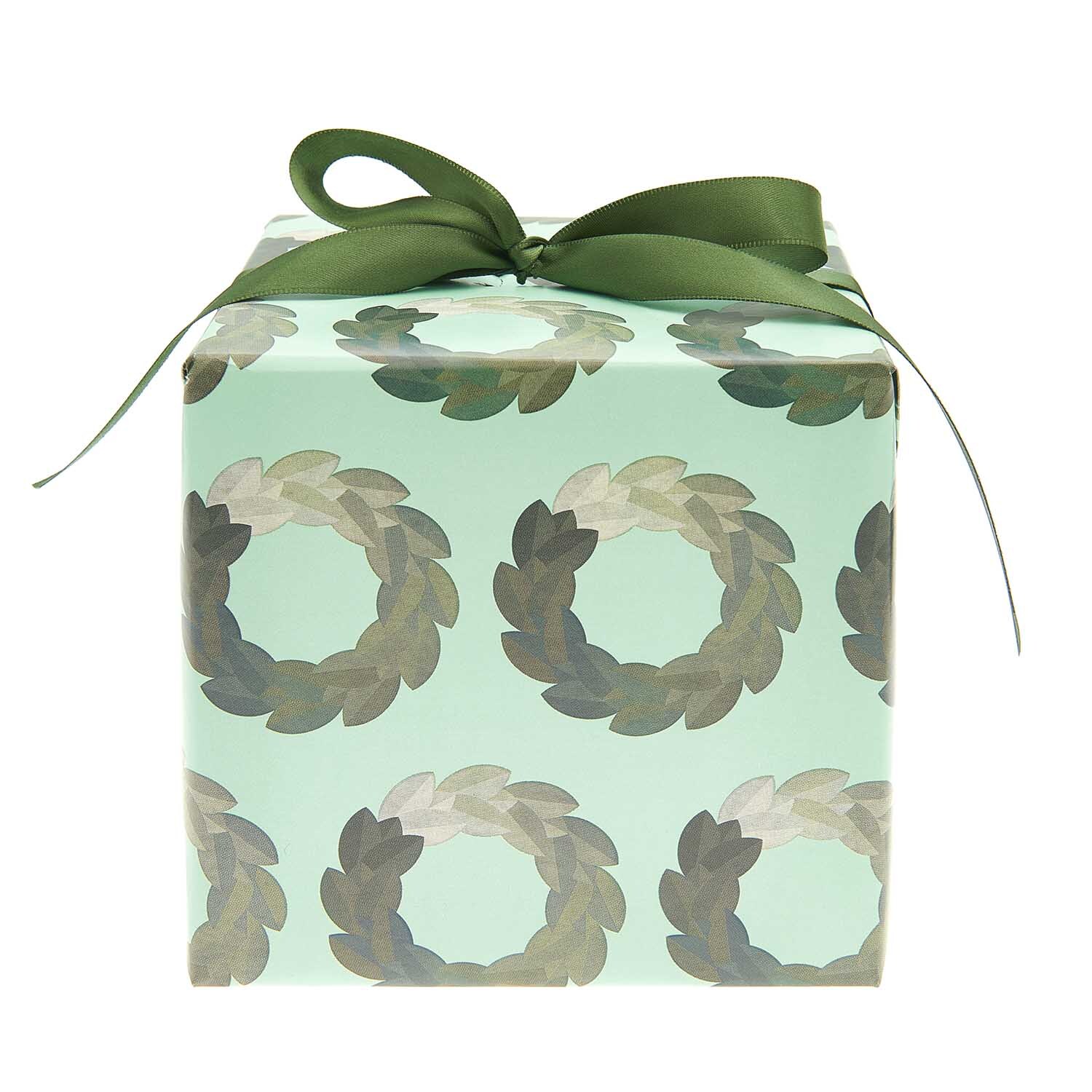 Paper Poetry Geschenkpapier mit Kranzmuster, verpackt als Geschenk mit grünem Band, von Rico Design.