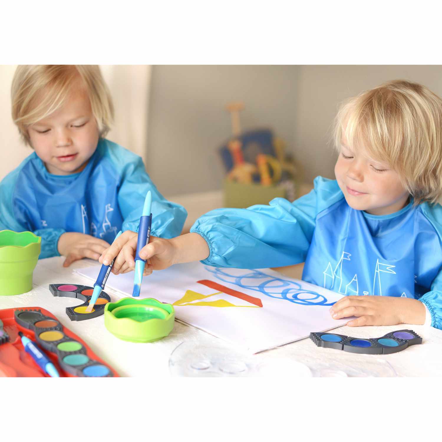 Malschürze für Kinder in Blau von Faber Castell: Zwei Kinder malen mit blauen Schürzen und Stiften.