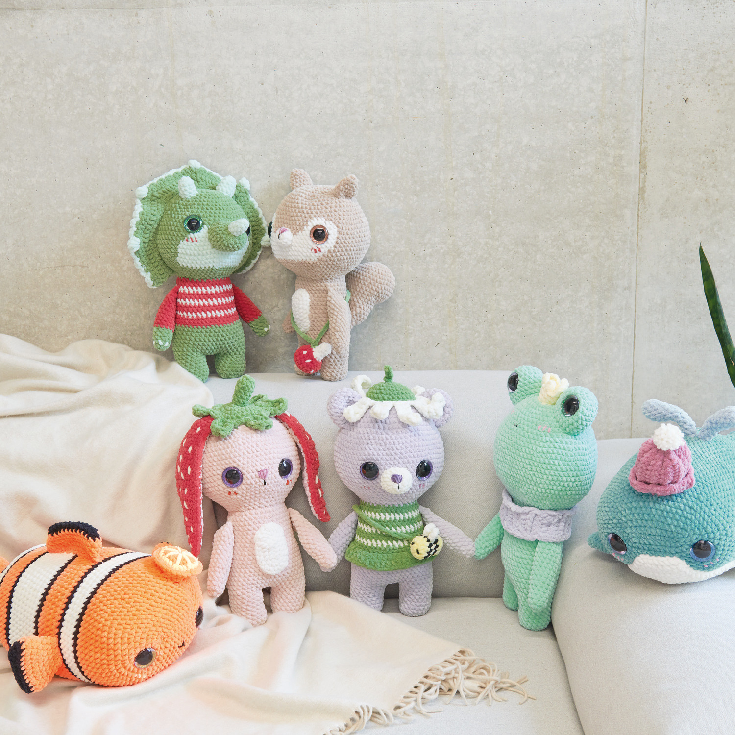 Häkelset Baby Dinosaur Modell 01 aus Chenillove Big Cuties: Bunte Häkeltiere auf Sofa.