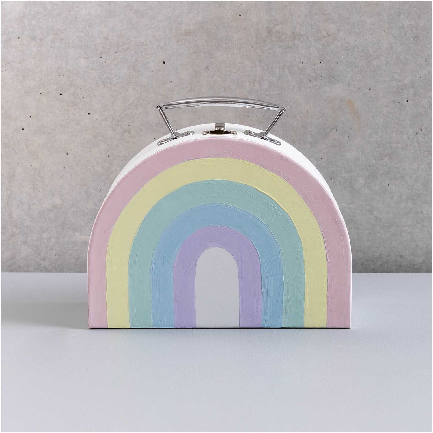 Koffer aus Pappe halbrund weiß mit Regenbogenmuster von Rico Design vor grauem Hintergrund.