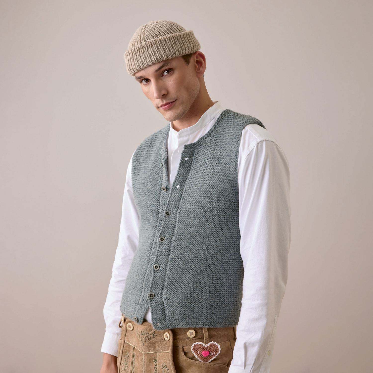 Strickset Herrenweste Modell 18 aus Trachtenbuch I mog di: Mann trägt gestrickte Weste und Mütze, kombiniert mit traditioneller Trachtenhose.