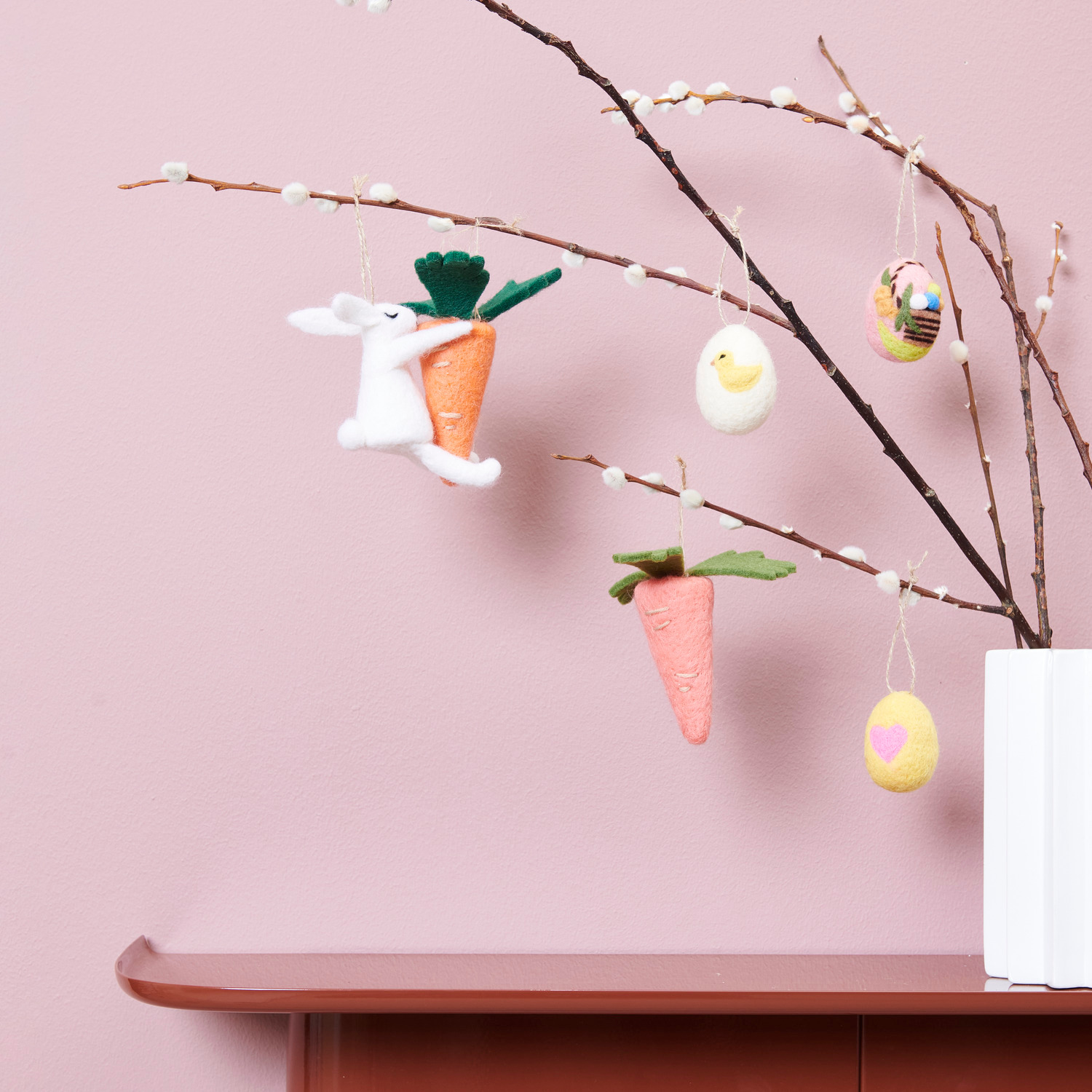 Filzhänger Hase Weiß: Dekorativer Ast mit Filzanhängern, darunter Hase, Küken und Möhre, von Rico Design.