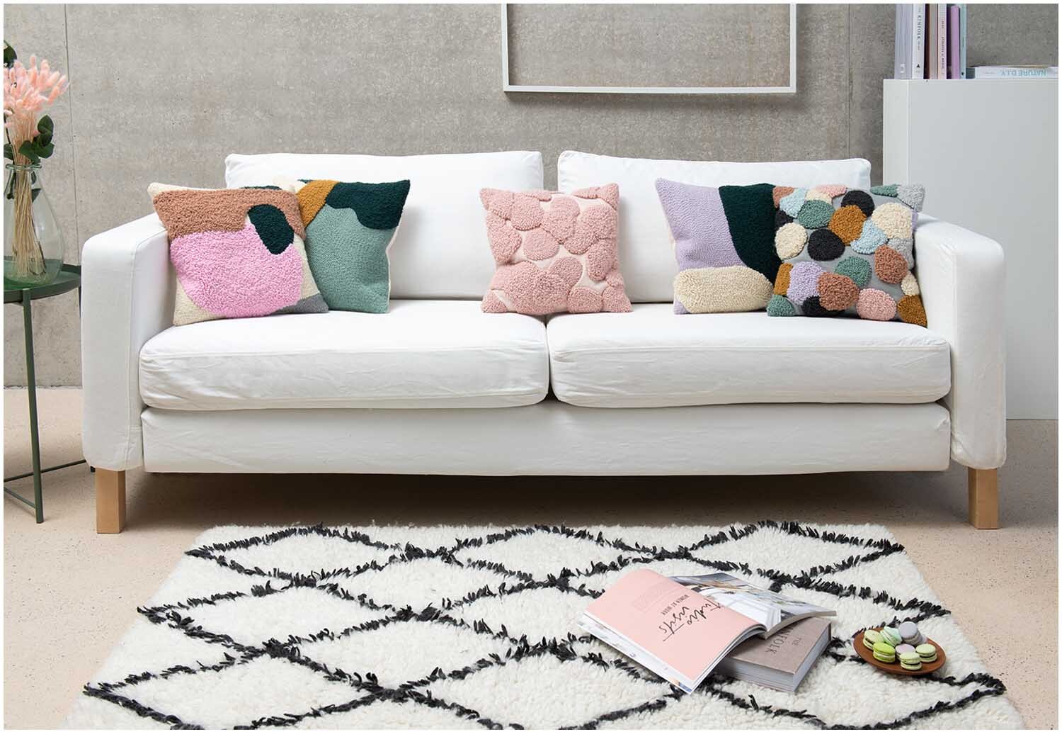 Punch Needle Packung Kissen Punkte rosa auf weißem Sofa mit bunten Kissen, modernes Wohnzimmerdekor.